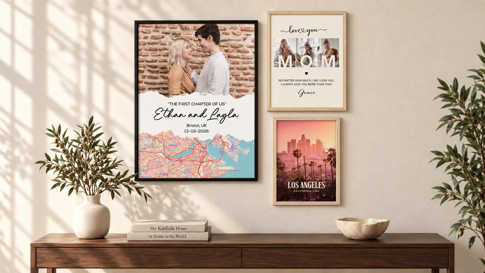 Three framed Joyie prints above a console table: a couple's photo and map poster, a 'love you Mom' print and a Los Angeles city poster